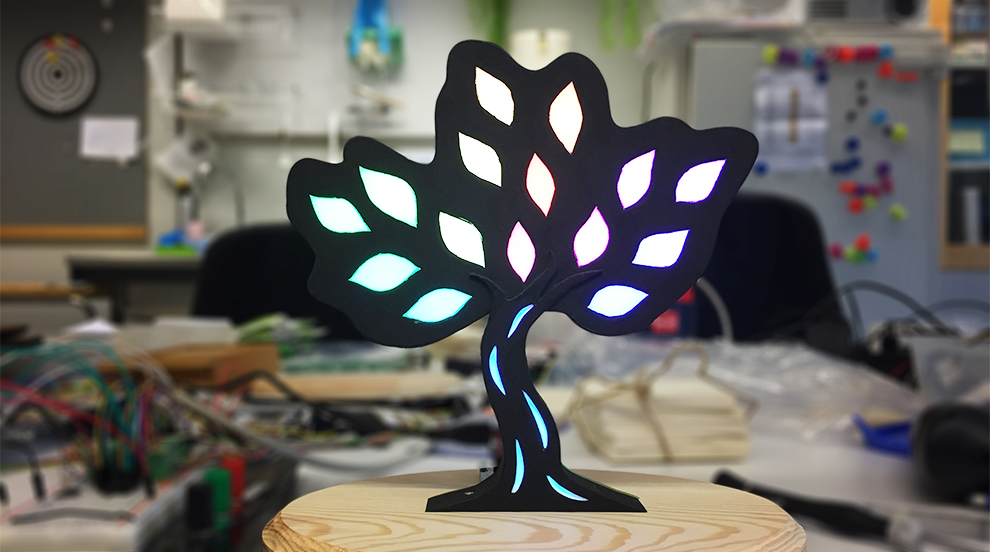 Ett träd med belysning stående på ett bord. Foto.